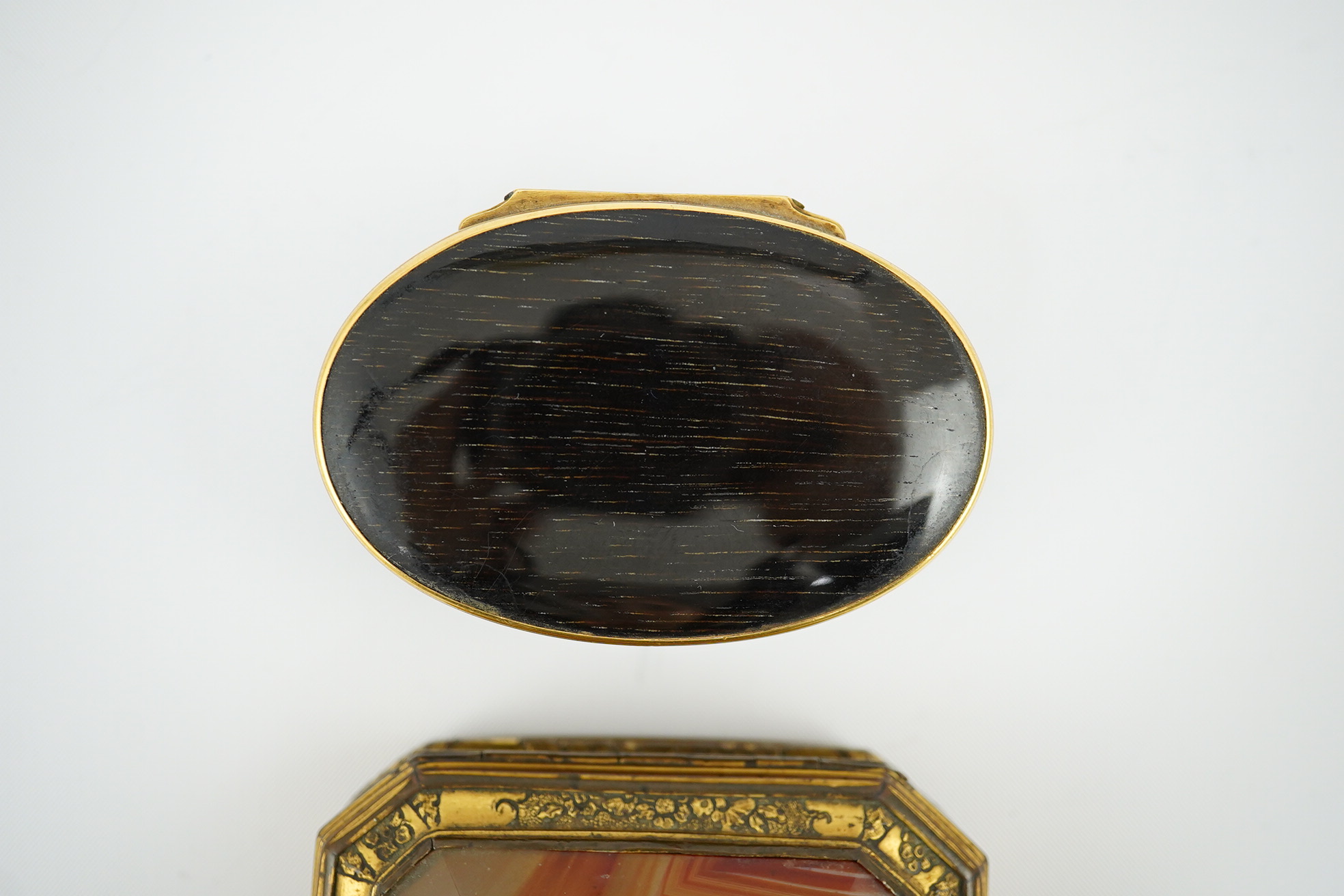 An early 19th century German gold mounted rutile agate? oval snuff box, 64mm and another gilt copper mounted agate snuff box.